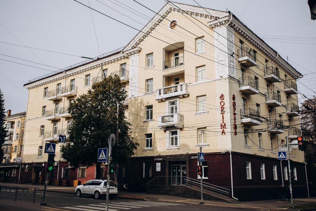 une voiture blanche garée devant un bâtiment dans l'établissement Optima Collection Chernihiv, à Tchernihiv