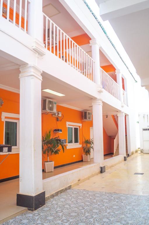 um edifício com paredes cor-de-laranja e colunas brancas em Legacy Apartment Phase 1 em Brufut