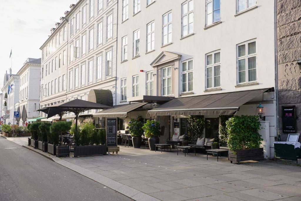 un bâtiment avec bancs et parasols dans une rue dans l'établissement Hotel Skt. Annæ, à Copenhague