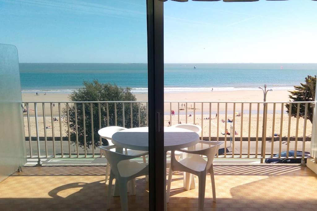 - un balcon avec une table et des chaises et la plage dans l'établissement Appartement pour 4/5 personnes, les pieds dans l'eau, à La Baule