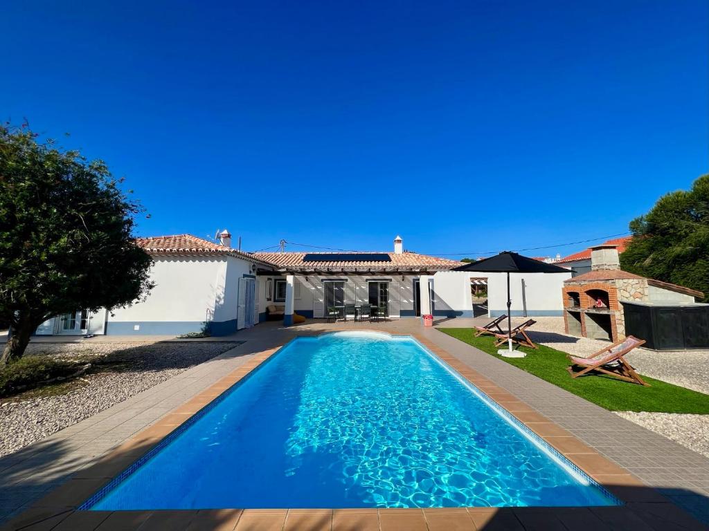 a villa with a swimming pool in front of a house at Canto do Vale in Aljezur