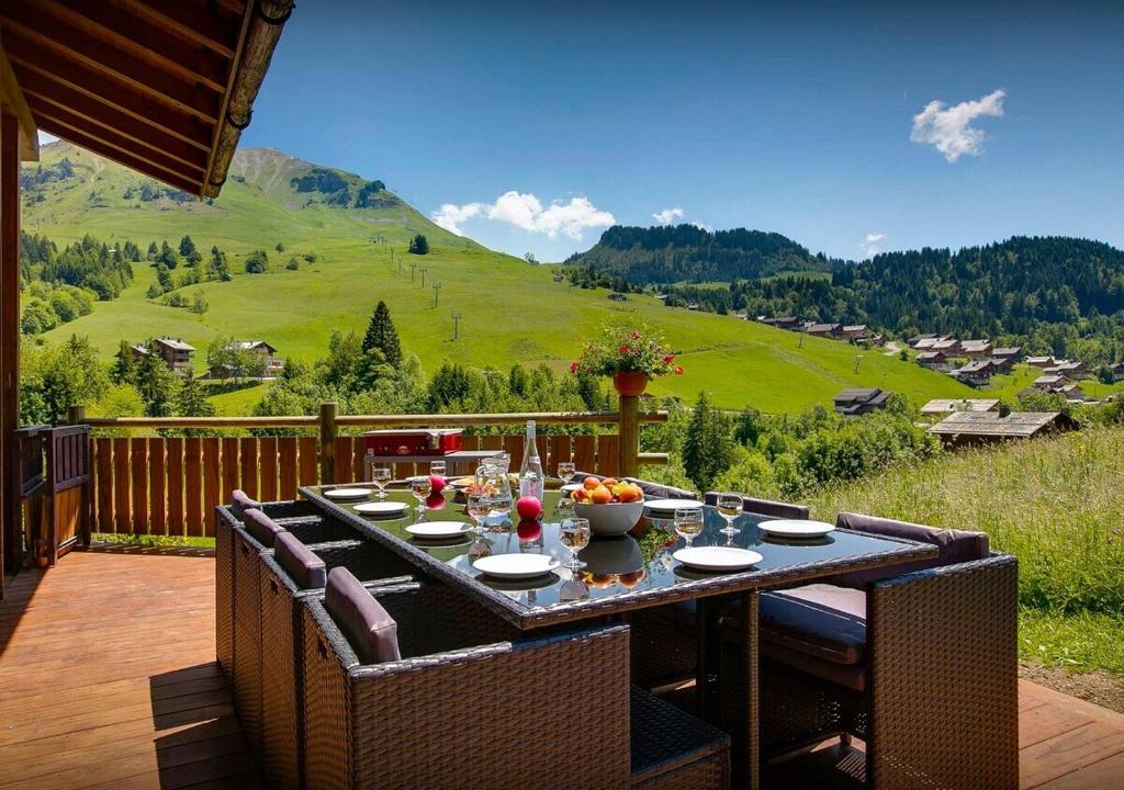 a table on a deck with a view of a mountain at Chalet Sicoria - Les Congères in Le Grand-Bornand