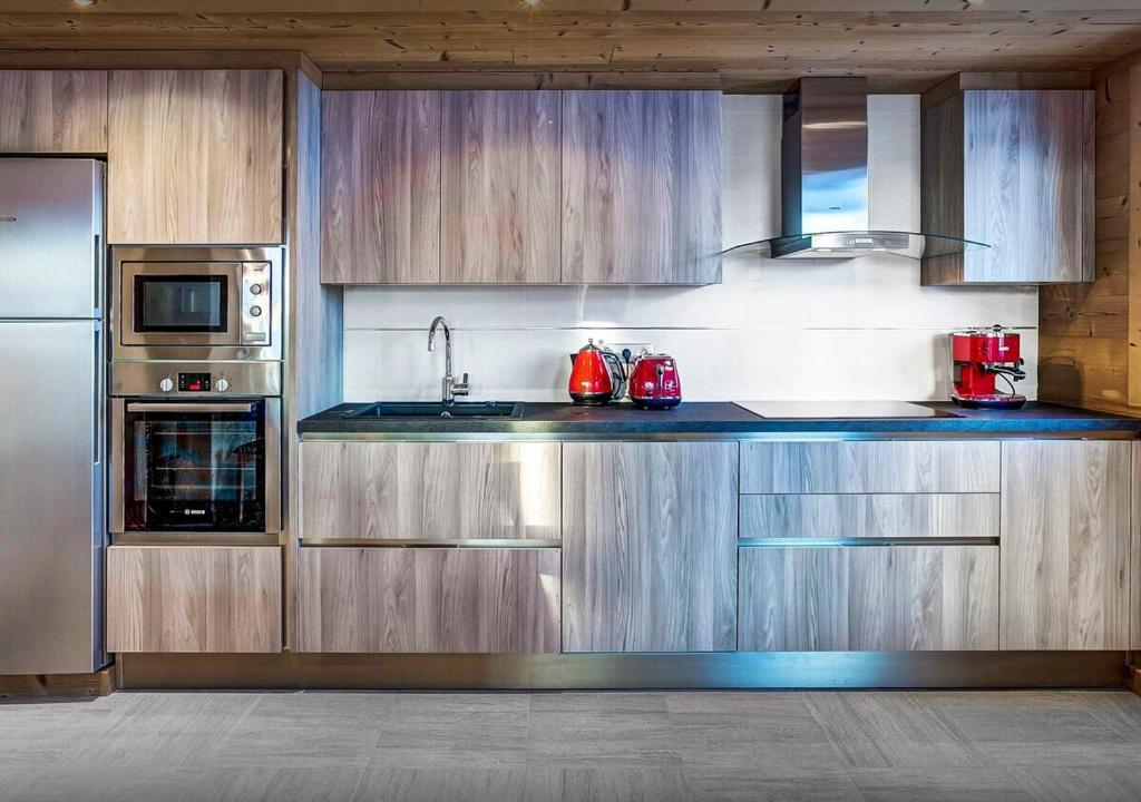 a kitchen with wooden cabinets and stainless steel appliances at Chalet Sicoria - Les Congères in Le Grand-Bornand