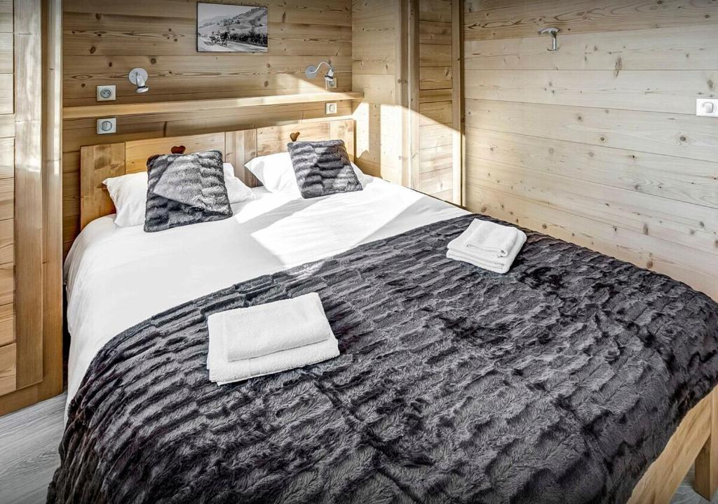 a bedroom with a large bed with wooden walls at Chalet Sicoria - Les Congères in Le Grand-Bornand