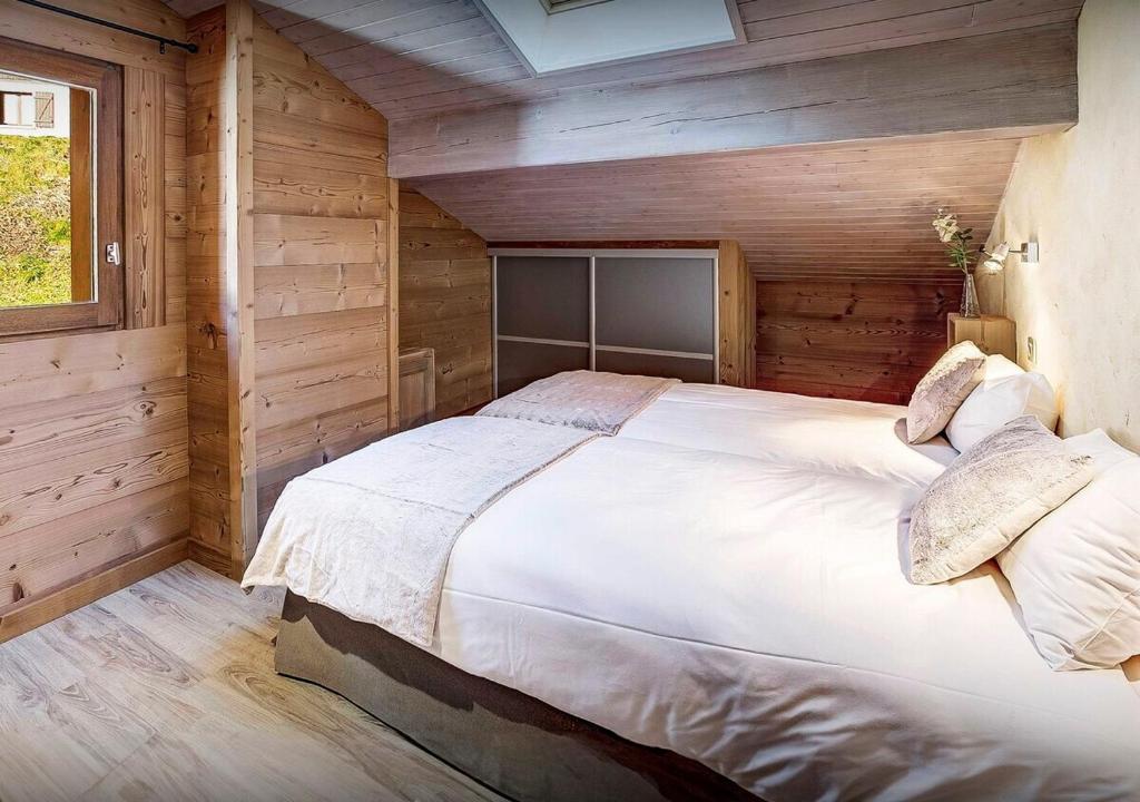 a bedroom with a large bed in a wooden room at Chalet Sicoria - Les Congères in Le Grand-Bornand