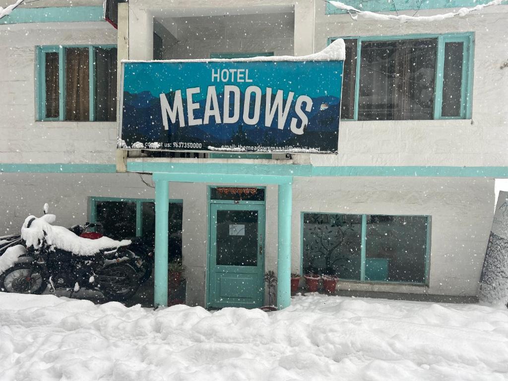 un cartello hotel Meadows sulla neve di fronte a un edificio di Hotel Himalayan Meadows a Manāli