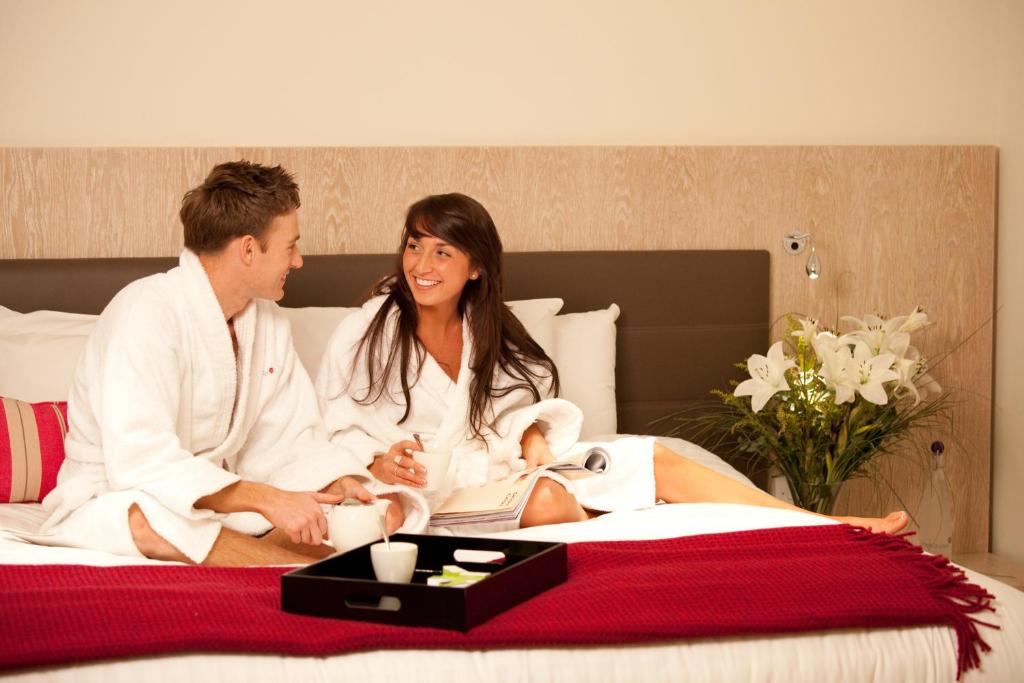 a man and a woman sitting on a bed at Lifehouse Spa And Hotel in Frinton-on-Sea