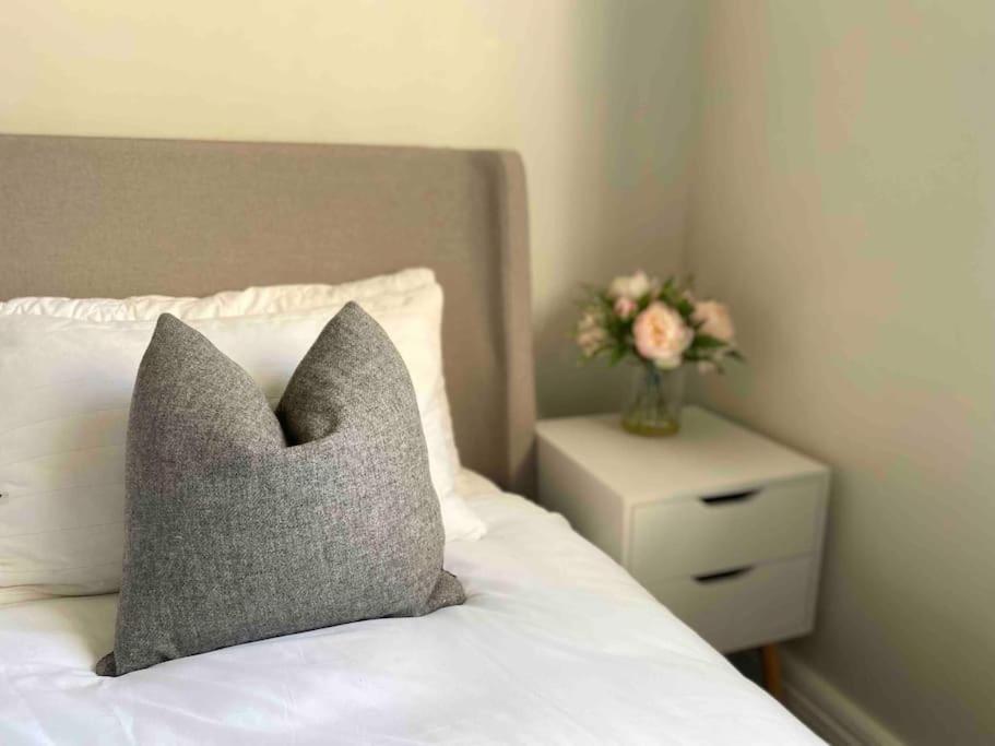 een kussen zittend op een bed met een vaas met bloemen bij Modern flat in Winchester