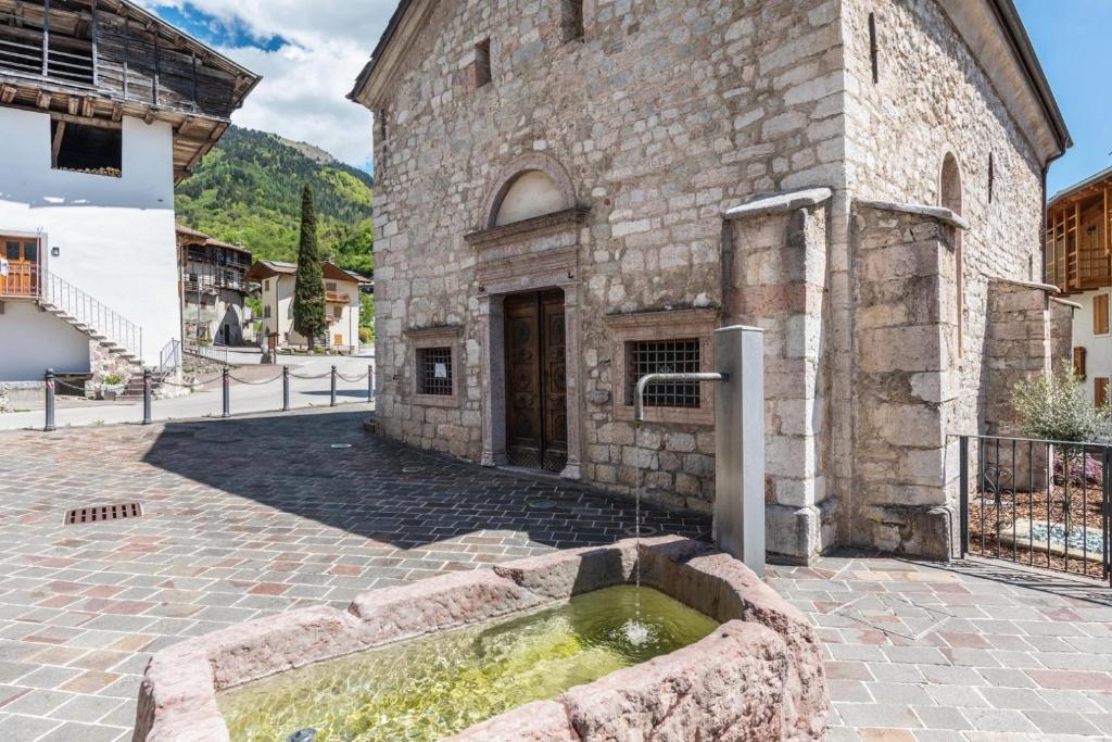 un edificio de piedra con una fuente de agua frente a él en Logge dei Paroloti, en Dorsino