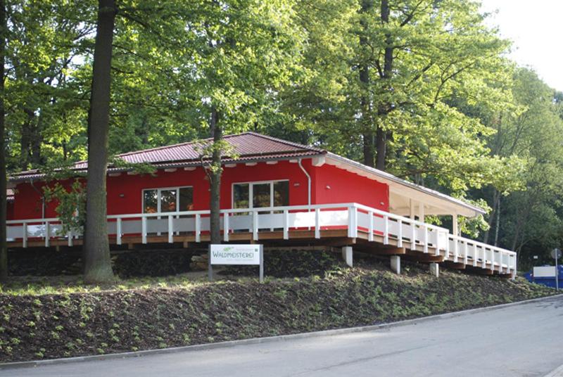 une maison rouge avec un panneau devant elle dans l'établissement Restaurant Waldmeisterei, à Gera