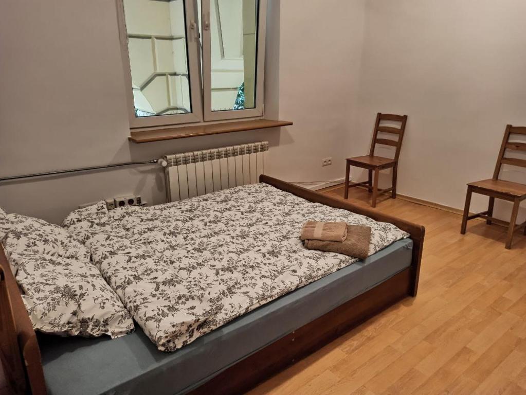 a bed in a room with two chairs and a window at Rooms in the Centrum in Warsaw