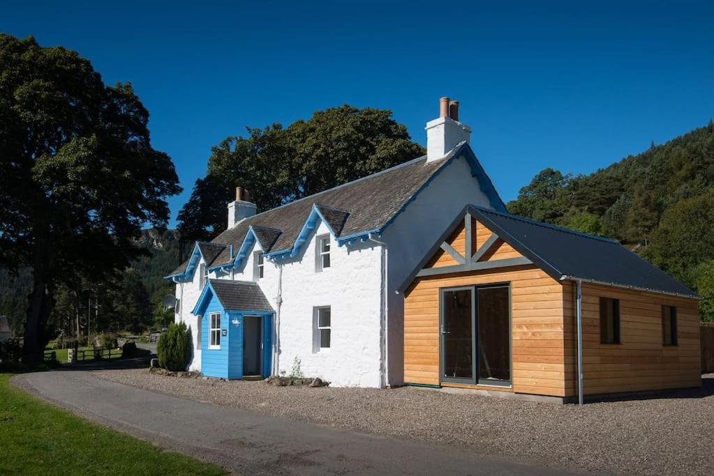 ein weißes und blaues Haus mit einem Gamer-Dach in der Unterkunft Keeper's Cottage, Straloch Estate in Perth