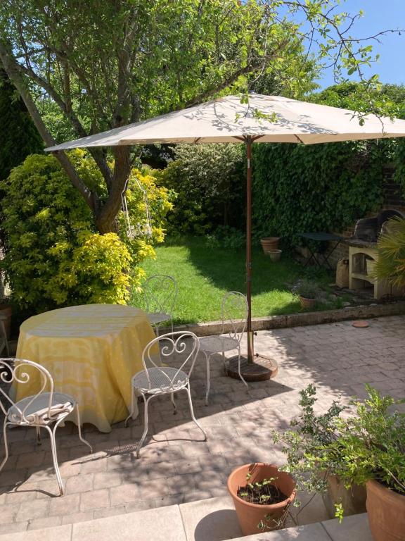 een tafel en stoelen onder een parasol op een patio bij Chambres en maison in Fontenay-sous-Bois