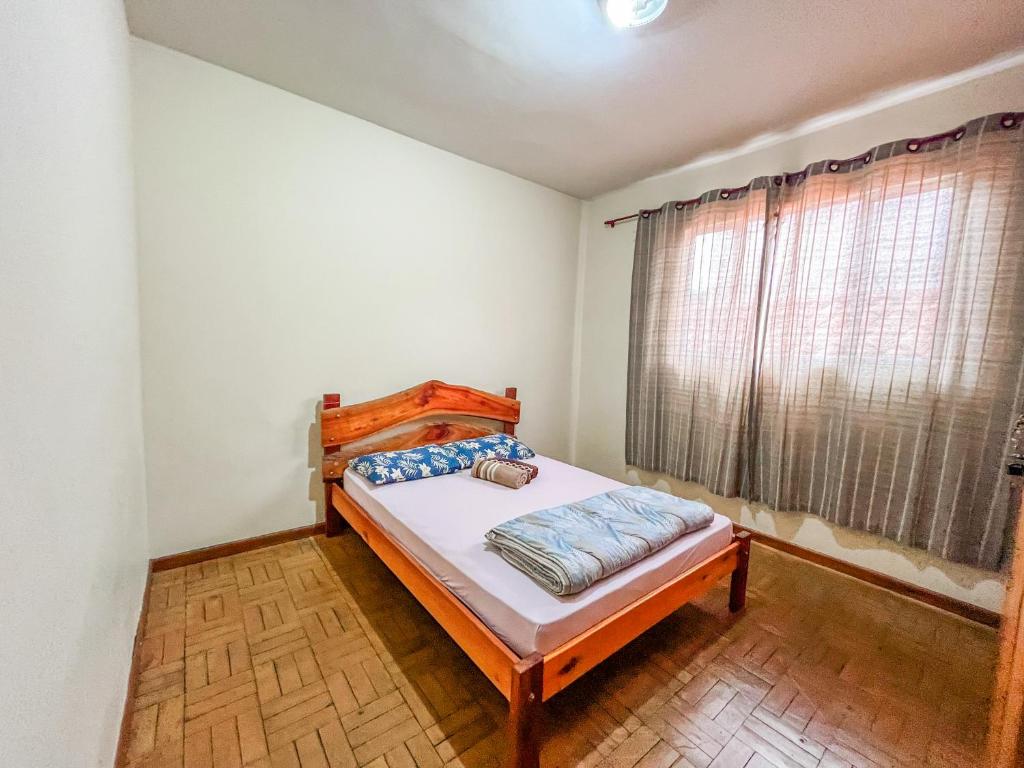 um quarto com uma cama e uma janela em Ótima casa no centro de Carrancas em Carrancas
