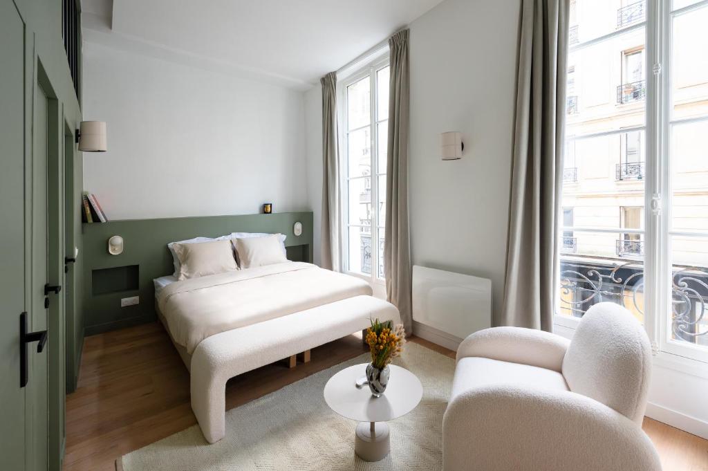 a bedroom with a bed and two chairs and a table at Noble Suites in Paris