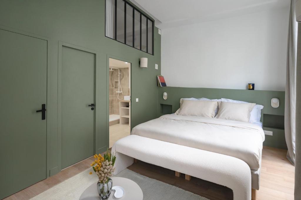 a bedroom with a large white bed and a green wall at Noble Suites in Paris