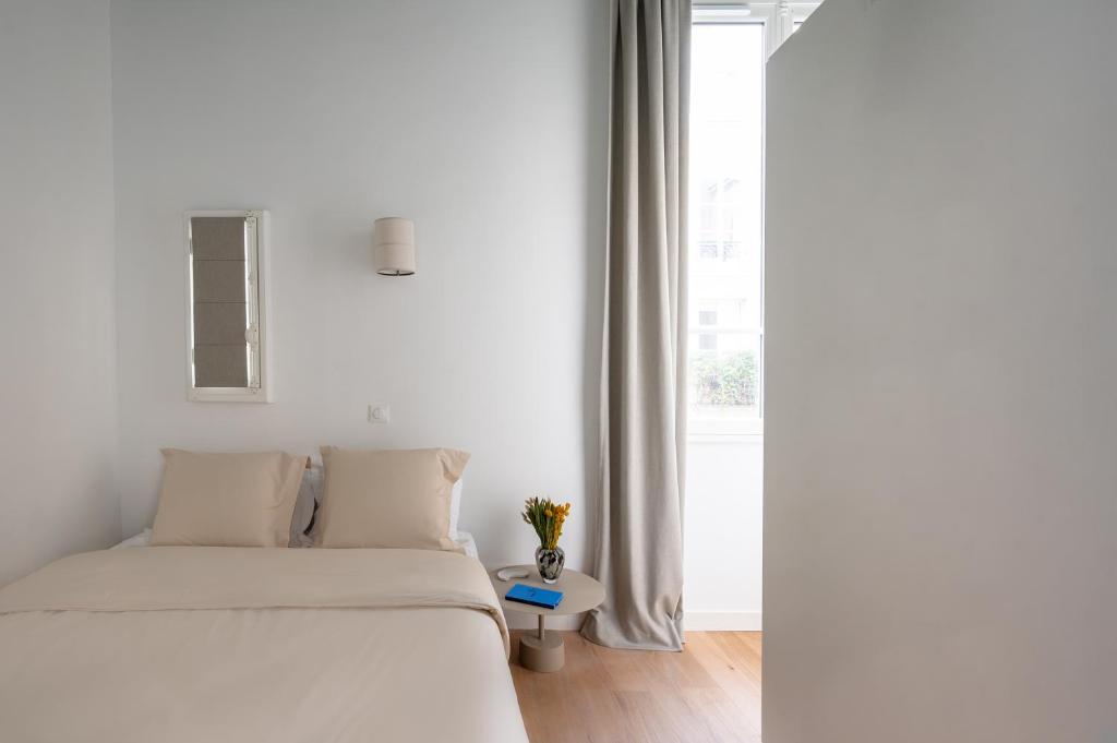 a white bedroom with a bed and a window at Noble Suites in Paris