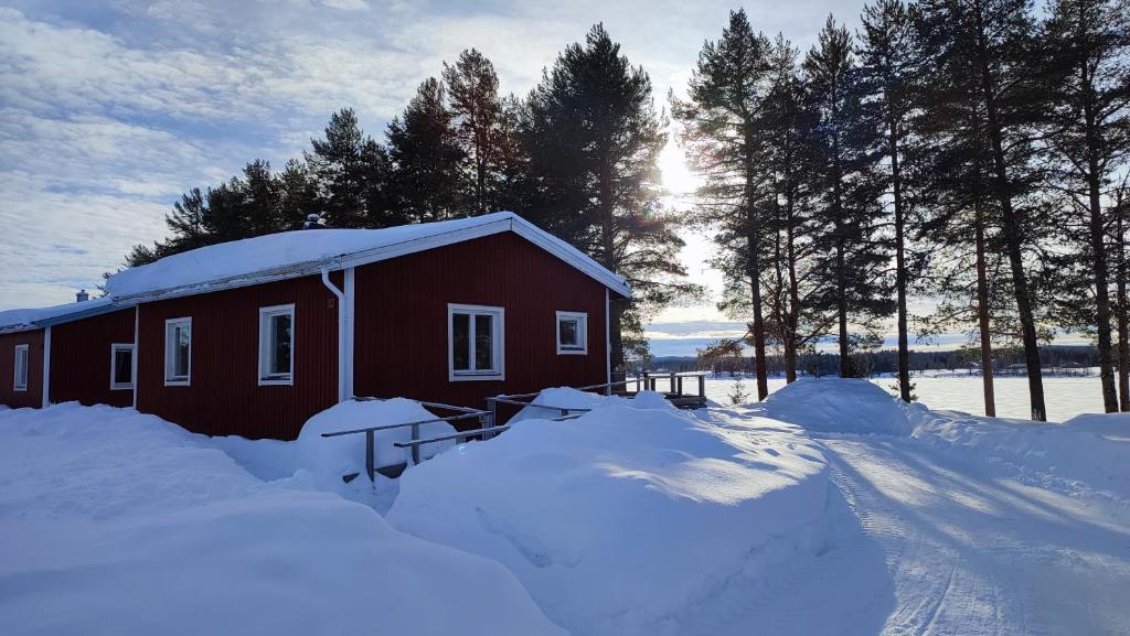 une maison recouverte de neige à côté d'un tas de neige dans l'établissement Fritidshus - Cottage - Holiday house - Soluppgång, à Blattniksele