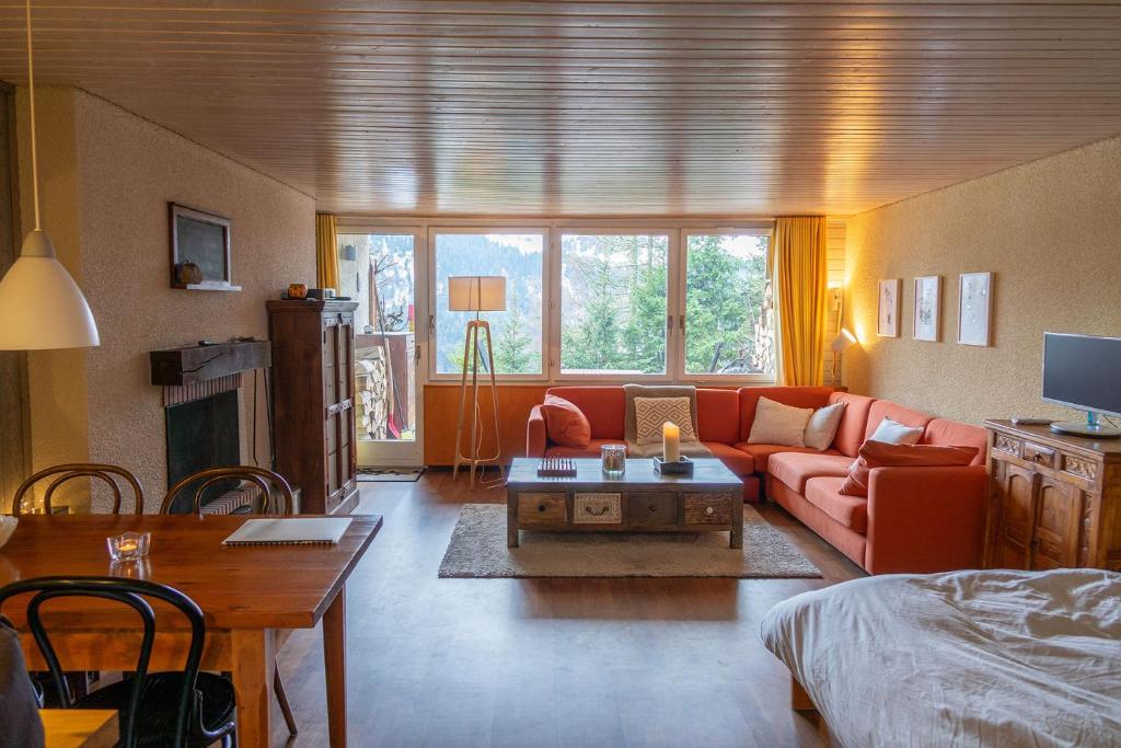 a living room with a red couch and a table at Cosy studio on the ski slopes in Gryon