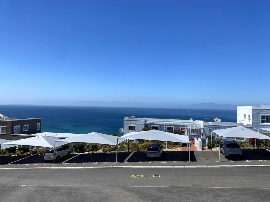 Una fila de sombrillas blancas frente a un edificio en Couples Cove: Luxe Getaway w/ jetted bath & views, en Ciudad del Cabo