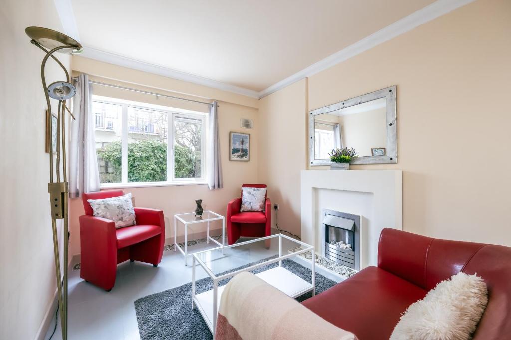 a living room with red chairs and a fireplace at Charming 2 Bed Apartment - 5mins to Aviva stadium in Dublin