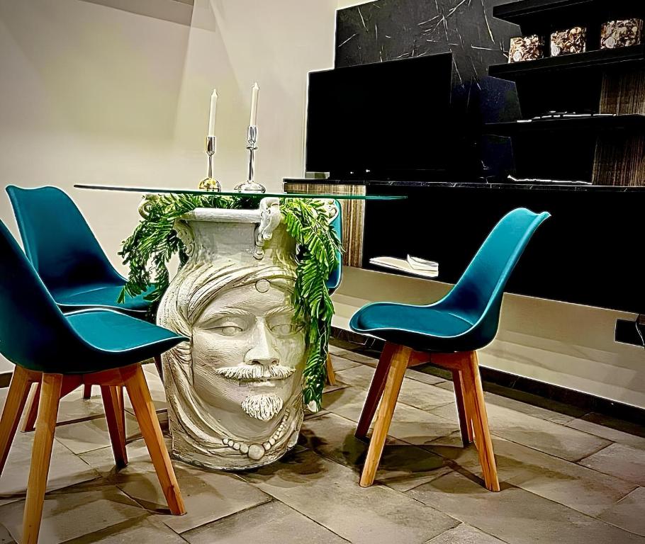 une table avec deux chaises et un grand vase dans l'établissement LAVIKA - Luxury Holiday Home, à Aci Trezza