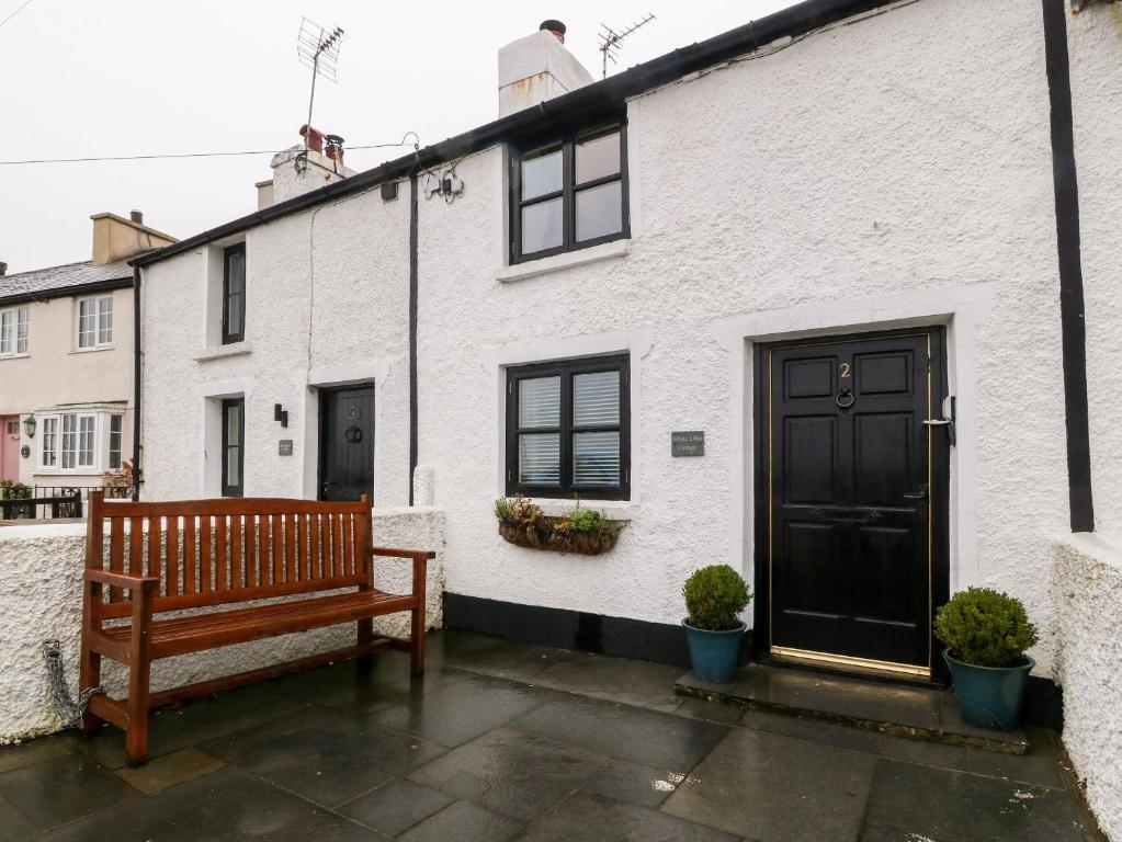 a wooden bench sitting in front of a white building at White Lilac Cottage in Llanfairpwllgwyngyll