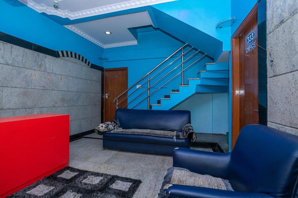 a living room with blue walls and blue stairs at OYO Royal Inn Near Iskcon Temple Bangalore in Bangalore