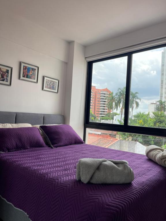 a purple bed in a room with a large window at ¡ACOGEDOR DEPTO. DE 2 DORMITORIOS CON PISCINA! in Santa Cruz de la Sierra