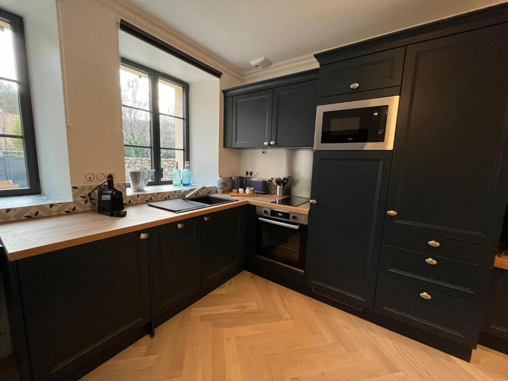 a kitchen with black cabinets and a wooden floor at Aux Quatre Petits clos in Jouars-Pontchartrain