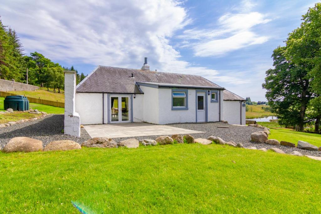 una pequeña casa blanca con un patio de césped en Glen Cottage en Cray