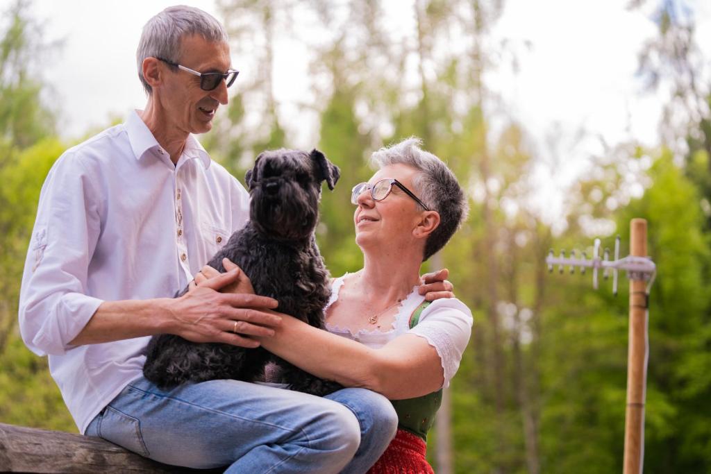 Ein Mann und eine Frau sitzen mit einem Hund auf einer Bank in der Unterkunft Agritur Dal Fior La Casa nel Bosco in Rundscheinberg