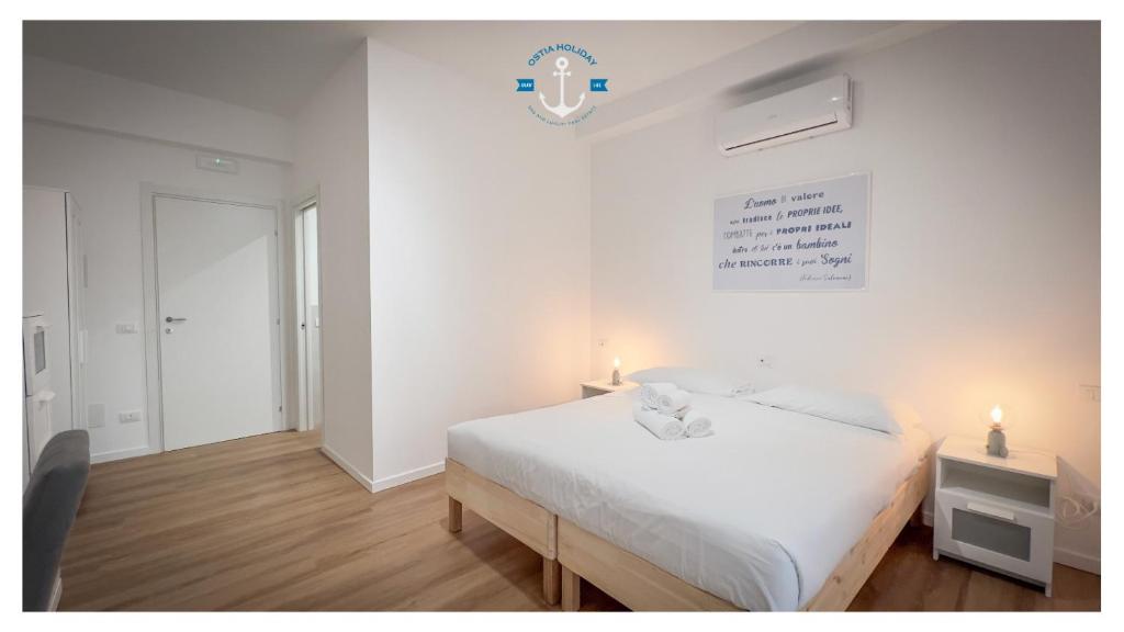 a white bedroom with a bed and a table with lights at La Dolce Sosta Executive in Lido di Ostia