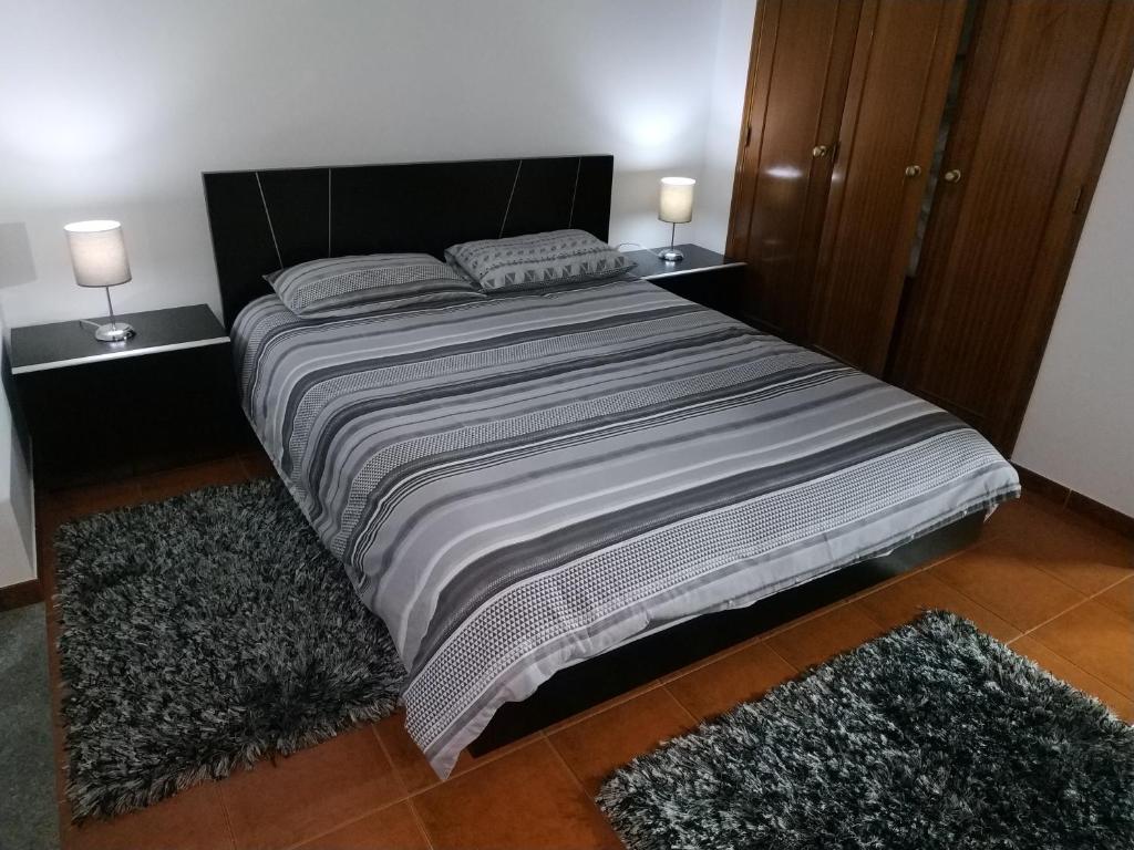 ein Schlafzimmer mit einem Bett mit zwei Nachttischen und zwei Teppichen in der Unterkunft Góis - Casa Belas Vistas - Rio e Montanha na N2 in Góis