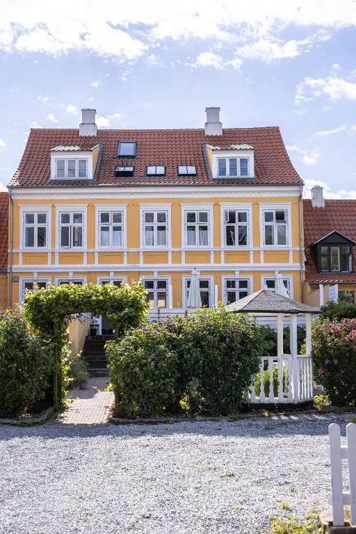 uma grande casa amarela com um telhado vermelho em Arnfeldt Hotel & Restaurant em Ærøskøbing