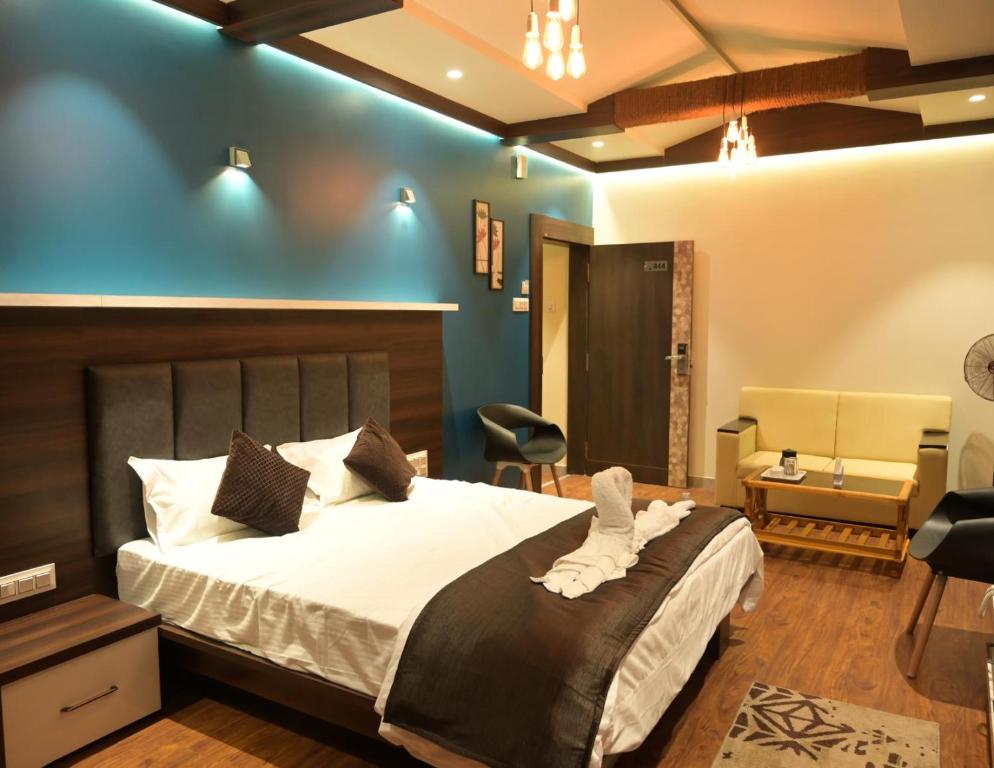 een slaapkamer met een groot bed met een blauwe muur bij Hotel Limelight in Kudāl