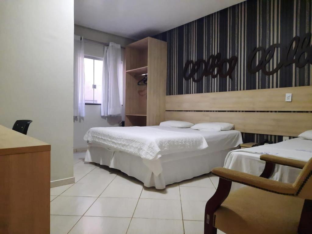 a bedroom with two beds and a sign on the wall at Laras Hotel Ltda in Acailandia