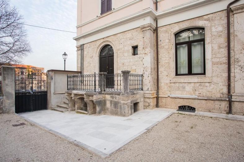 un gran edificio de ladrillo con un balcón delante de él en Villino Mari, en Ascoli Piceno