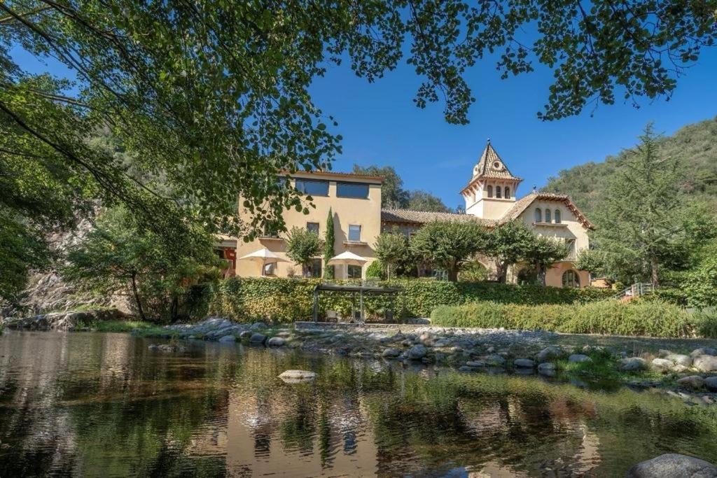 une maison sur une colline à côté d'une rivière dans l'établissement Hotel Spa La Central - Adults Only, à Maçanet de Cabrenys