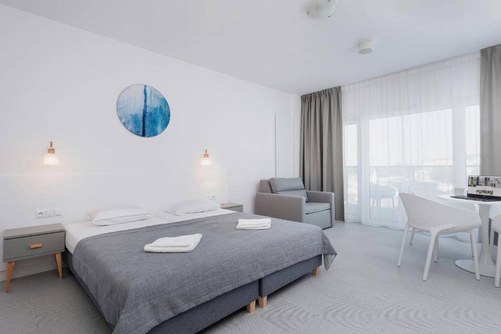 a bedroom with a bed and a table and a chair at Aquamarina Prima 049 by Renters in Międzyzdroje