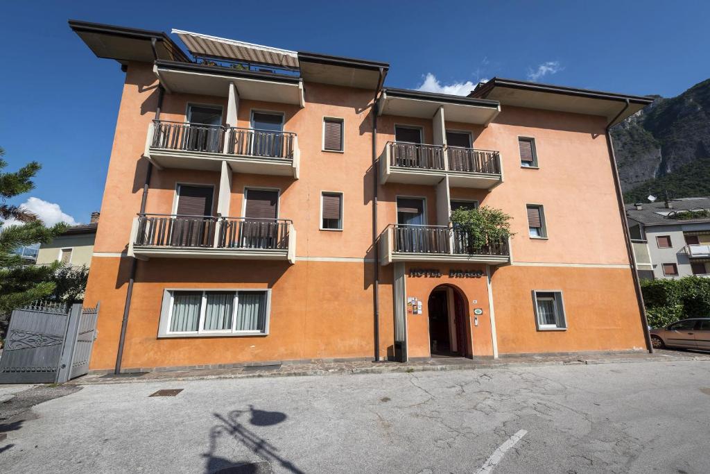 un grand bâtiment orange avec balcon dans une rue dans l'établissement Hotel Drago, à Mezzocorona