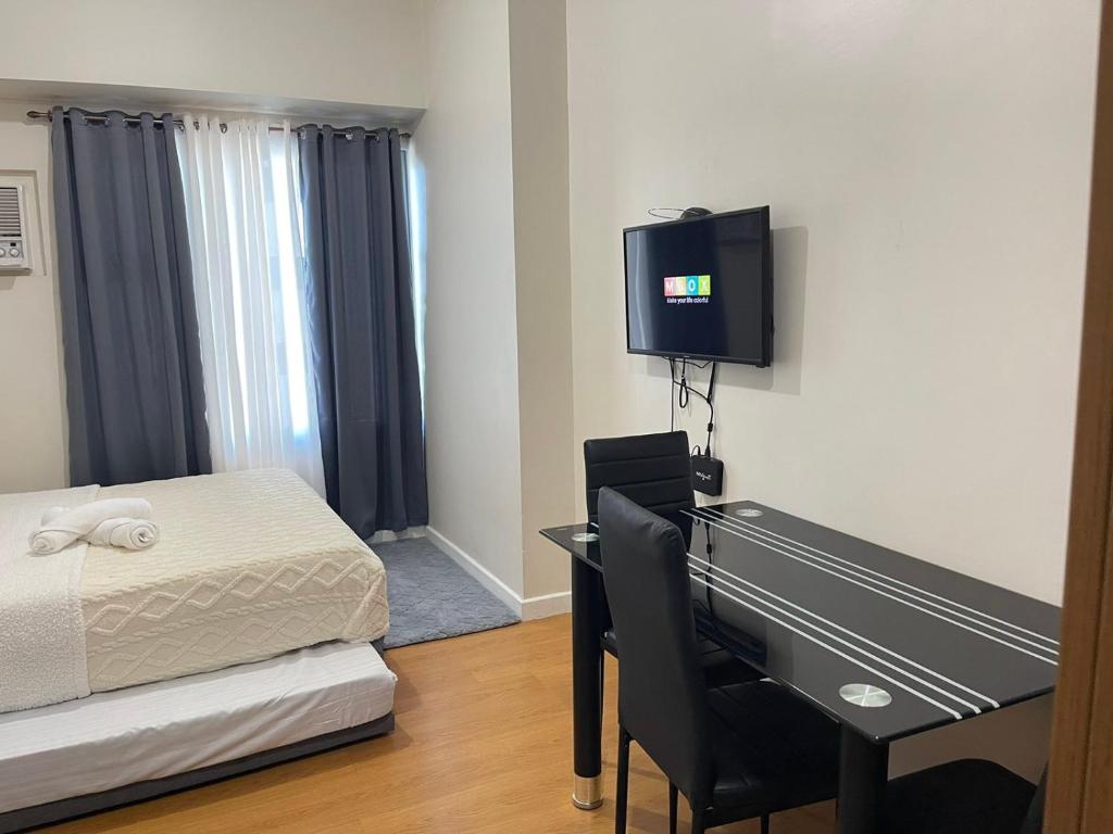 a bedroom with a bed and a desk and a television at Modern Condo near US Embassy and St Lukes Ermita in Manila