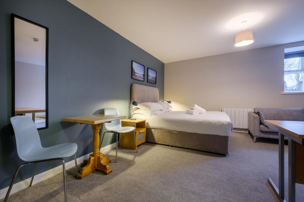 a hotel room with a bed and a table and chairs at Station Lodge - FREE off-site Health Club access with Pool, Sauna, Steam Room & Gym in Windermere