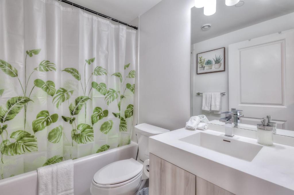 e bagno con servizi igienici e tenda da doccia con piante. di RivetStays - The Jarvis a Toronto