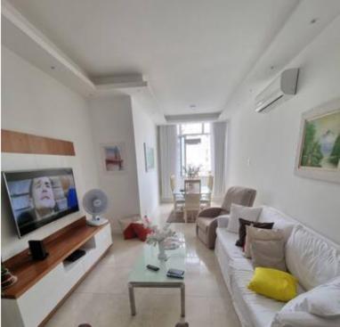 uma sala de estar com um sofá e uma televisão em Quarto confortavel privativo Copacabana no Rio de Janeiro