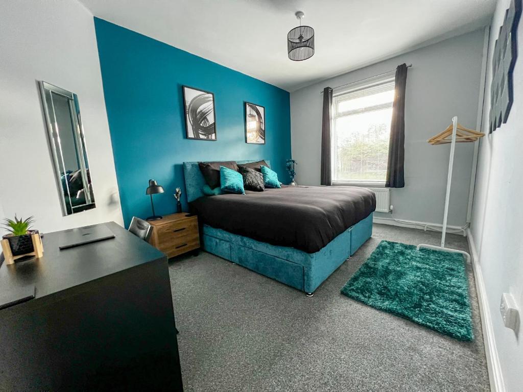a bedroom with a bed and a blue wall at The Grey Bungalow in Waterhouses