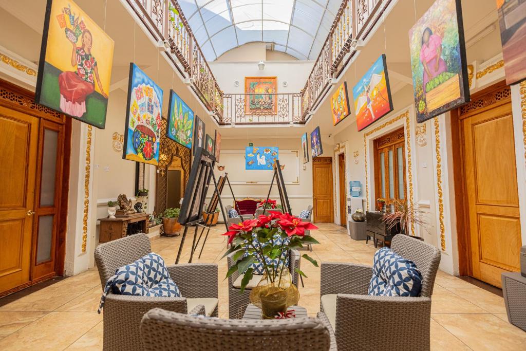 a lobby with chairs and paintings on the walls at Hotel Patio Pombo in Oaxaca City
