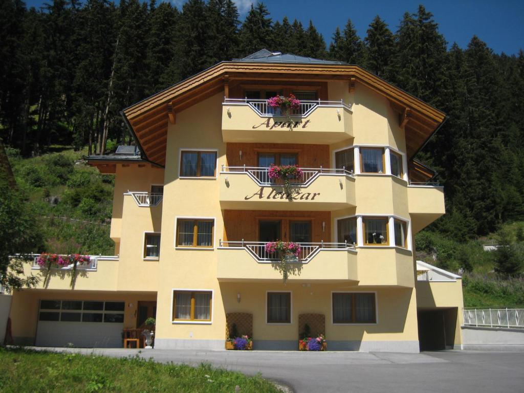 un gran edificio amarillo con cajas de flores. en Apart Alcazar en Ischgl