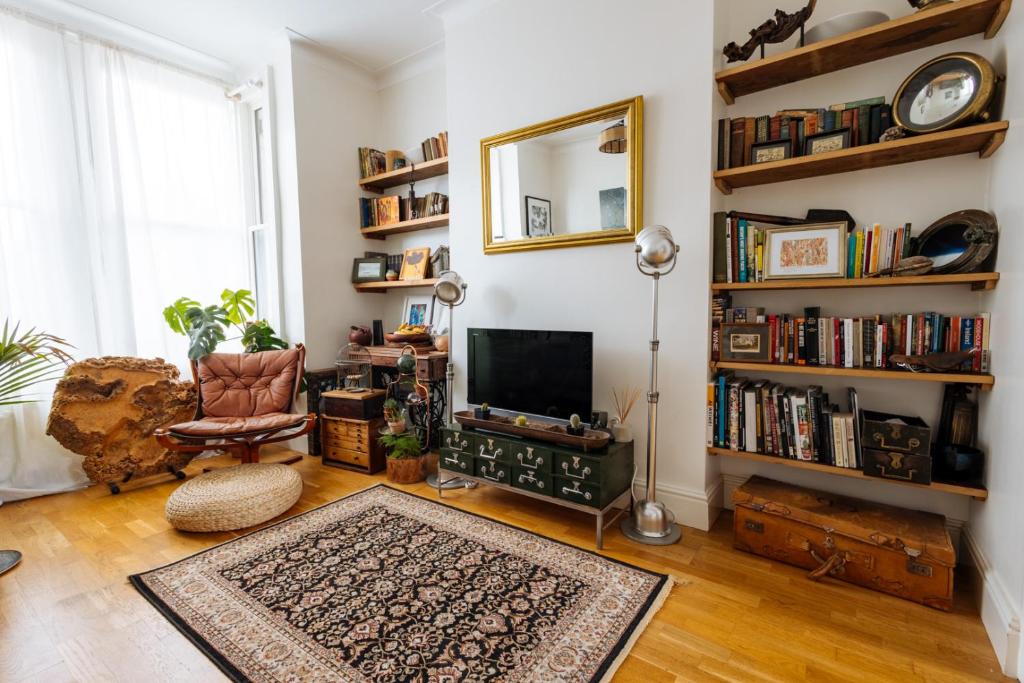 a living room with a television and a book shelf at Comfy 1-Bed Apartment in London in London
