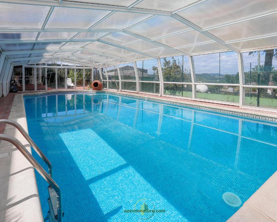 une grande piscine avec un toit clair dans l'établissement Casa com Piscina Cinema Discoteca Ginásio, à Ermegil